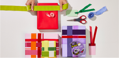 Manos envolviendo cajar de regalos con envolturas originales en color morado y rojo, packshot Cinta de Regalos Giftwrap Scotch®.
