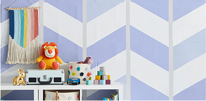 Diseño pintado en pared con Cinta ScotchBlue™ y accesorios de bebés y niños en repisa.
